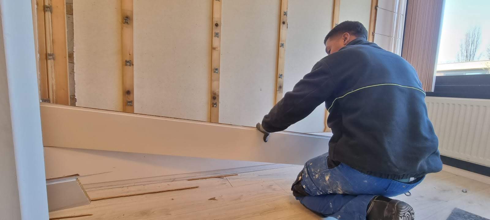 J.C. Multiservices team member fitting a wall panel during an interior renovation